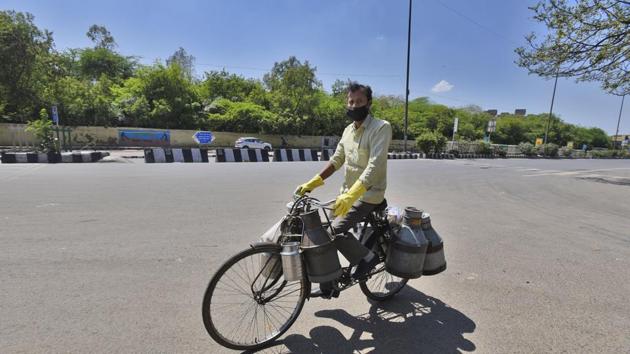 A milk vendor rides his bicycle on a deserted road in Delhi.(Burhaan Kinu/HT PHOTO)