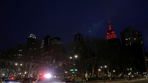 New York Police Department vehicles drive along 42nd Street as the Empire State Building is lit in red to honor emergency workers during the outbreak of coronavirus disease (COVID-19) in Manhattan, New York City.(REUTERS)