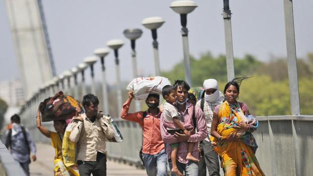 Daily wage laborers holding their children walk on foot to their respective villages following a lockdown amid concern over spread of coronavirus, on the outskirts of Prayagraj, India.(AP) Daily wage laborers holding their children walk on foot to their respective villages following a lockdown amid concern over spread of coronavirus, on the outskirts of Prayagraj, India.(AP)