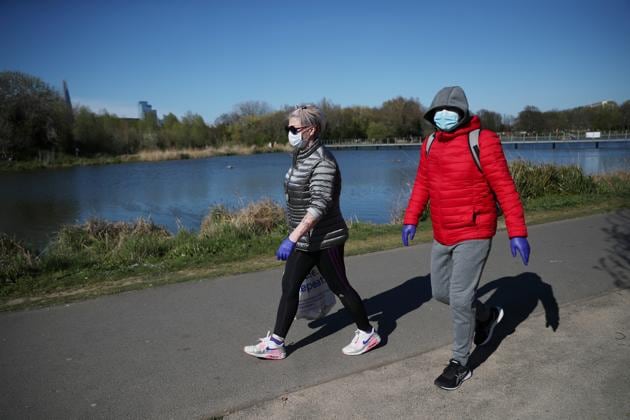 A woman and man wearing protective masks walk in Burgess Park, as the spread of the coronavirus disease (COVID-19) continues, London, Britain, April 5, 2020. (REUTERS)