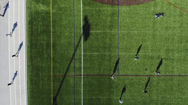 Northeastern University students kick a football around while social distancing on a field as others run around the track, in Boston. The students usually have three times as many people meet for their regular pick-up games but many went home after the school closed over Covid-19 infection fears. (David Goldman / AP) Northeastern University students kick a football around while social distancing on a field as others run around the track, in Boston. The students usually have three times as many people meet for their regular pick-up games but many went home after the school closed over Covid-19 infection fears. (David Goldman / AP)