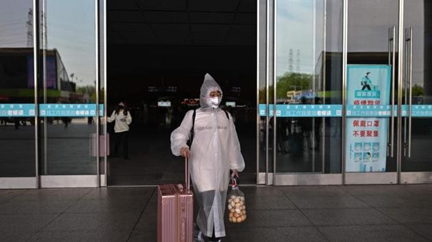 A woman wearing protective clothes and a face mask arrives at the railway station in Wuhan, in China's central Hubei province on April 6, 2020.(AFP)