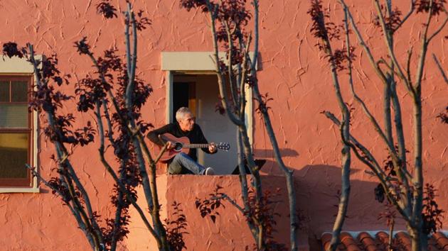 Danny Wertheimer plays the guitar and sings to his neighbours from his balcony after California’s Governor Gavin Newsom implemented a state wide “stay at home order” directing the state’s 40 million residents to stay in their homes for the foreseeable future in Oakland. (Kate Munsch / REUTERS)