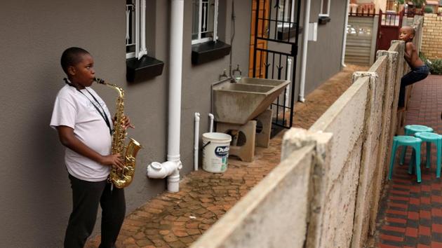 Ntsika Ntsele, 13, plays an alto saxophone while his neighbour looks on over a fence, during a three-week nationwide lockdown to try to contain the coronavirus outbreak, in Soweto, South Africa. (Siphiwe Sibeko / REUTERS)