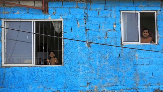 A man and a boy look out from the windows of their home during a curfew imposed by the government in Colombo, Sri Lanka. (Dinuka Liyanawatte / REUTERS)