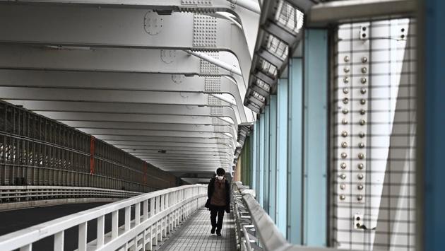 A lone man walks on the Rainbow Bridge in Tokyo on April 7. Coronavirus infections in Tokyo more than doubled to about 1,200 cases in the past week. (Philip Fong / AFP) A lone man walks on the Rainbow Bridge in Tokyo on April 7. Coronavirus infections in Tokyo more than doubled to about 1,200 cases in the past week. (Philip Fong / AFP)