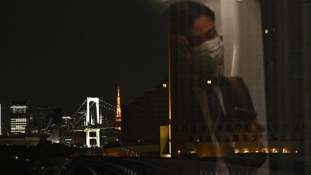A view of Rainbow Bridge (L) and Tokyo tower (C) from a train as a passenger wearing a face mask travels in Tokyo on April 7. (Philip Fong / AFP) A view of Rainbow Bridge (L) and Tokyo tower (C) from a train as a passenger wearing a face mask travels in Tokyo on April 7. (Philip Fong / AFP)