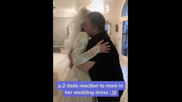 The dad gets a surprised look on his face after his wife walks in wearing the wedding gown. (snoozysusie//official TikTok) The dad gets a surprised look on his face after his wife walks in wearing the wedding gown. (snoozysusie//official TikTok)