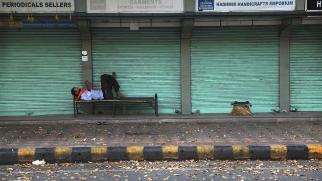 A private security guard checks his mobile phone while resting in front of closed market during the nation wide 21 day lockdown amid concern over the spread of coronavirus in New Delhi, India.(AP)