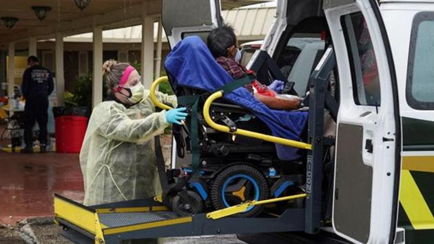 A healthcare worker in protective suits helps an elderly person to get off an ambulance at the Southeast Nursing and Rehabilitation Center nursing home during the coronavirus epidemic. (Reuters Photo)