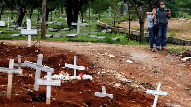 Relatives wearing face masks stand next to graves of coronavirus victims at a cemetery area provided by the government in Jakarta, Indonesia. Funerals are being witnessed by just a few people and last a brief while, ending without embraces. (Willy Kurniawan / REUTERS) Relatives wearing face masks stand next to graves of coronavirus victims at a cemetery area provided by the government in Jakarta, Indonesia. Funerals are being witnessed by just a few people and last a brief while, ending without embraces. (Willy Kurniawan / REUTERS)