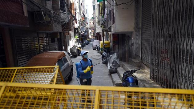 An MCD worker sprays disinfectant while sanitizing the West Vinod Nagar area which has been declared a containment zone, on day sixteen of the 21 day nationwide lockdown to limit the spread of coronavirus in New Delhi.(Ajay Aggarwal/HT PHOTO)