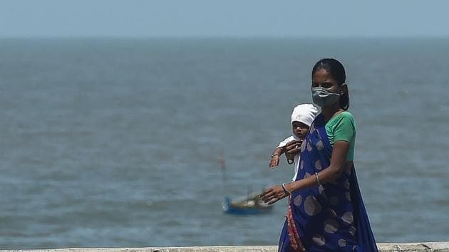 A woman wearing a facemask walks along a promenade carrying a child during a government-imposed nationwide lockdown as a preventive measure against the COVID-19 coronavirus, in Mumbai, India on April 9, 2020.(AFP)