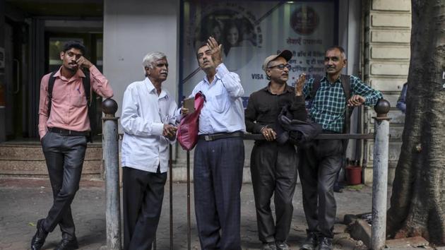 People look up at a screen and electronic ticker board, not pictured, outside the Bombay Stock Exchange (BSE) building in Mumbai.(Bloomberg)