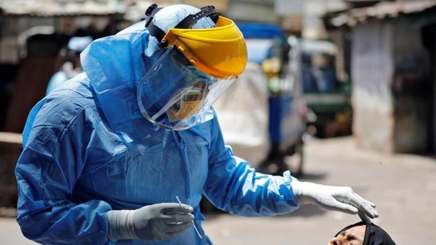 A doctor wearing protective gear prepares to take a swab from a girl to test for coronavirus disease (COVID-19) at a residential area in Ahmedabad. (REUTERS)