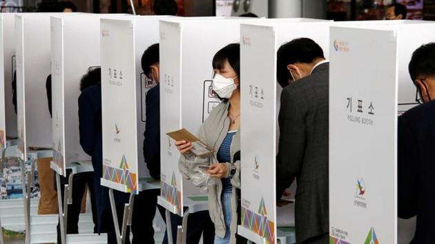 A woman wearing a mask to prevent contracting the coronavirus leaves a voting booth to cast her absentee ballot for the parliamentary election at a polling station in Seoul, South Korea on April 10, 2020.(Reuters photo) A woman wearing a mask to prevent contracting the coronavirus leaves a voting booth to cast her absentee ballot for the parliamentary election at a polling station in Seoul, South Korea on April 10, 2020.(Reuters photo)