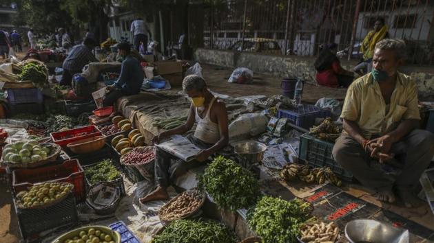 A vegetable vendor wearing protective face masks waits for customers at a market during a lockdown imposed due to the coronavirus in Mumbai.(Bloomberg)