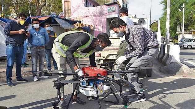 Municipal corporation workers equip a disinfectant pack to a drone, to sanitise narrow lanes and hot spots to prevent the spread of Covid-19.(Sanchit Khanna / HT File)