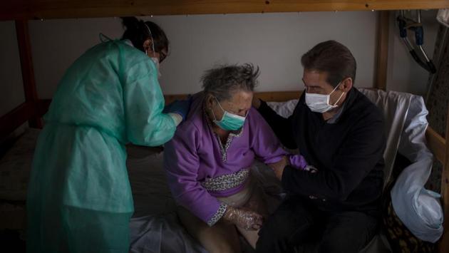 A home care doctor performs a physical exam on Felicidad while her son, Joan, holds her arm at her home. Felicidad had been admitted to the hospital after suffering a stroke but was sent home within a day and soon developed respiratory symptoms. As in similarly hard-hit Italy, Spain’s elderly aren’t usually being tested for COVID-19. (Emilio Morenatti / AP) A home care doctor performs a physical exam on Felicidad while her son, Joan, holds her arm at her home. Felicidad had been admitted to the hospital after suffering a stroke but was sent home within a day and soon developed respiratory symptoms. As in similarly hard-hit Italy, Spain’s elderly aren’t usually being tested for COVID-19. (Emilio Morenatti / AP)