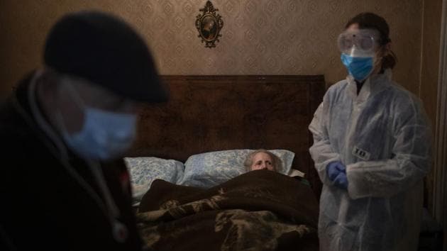 Josefa Ribas, 86, who is bedridden, looks at nurse Alba Rodriguez as Ribas’ husband, Jose Marcos, 89, stands by in their home in Barcelona, Spain. Ribas suffers from dementia, and Marcos fears for them both if the coronavirus enters their home. “If I get the virus, who will take care of my wife?” (Emilio Morenatti / AP) Josefa Ribas, 86, who is bedridden, looks at nurse Alba Rodriguez as Ribas’ husband, Jose Marcos, 89, stands by in their home in Barcelona, Spain. Ribas suffers from dementia, and Marcos fears for them both if the coronavirus enters their home. “If I get the virus, who will take care of my wife?” (Emilio Morenatti / AP)