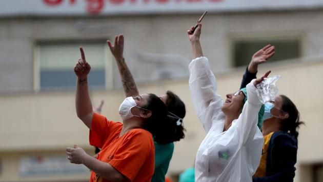 Medical staff react after hearing a helicopter flying overhead, while people applaud in support for healthcare workers in Madrid, Spain. (Susana Vera / REUTERS) Medical staff react after hearing a helicopter flying overhead, while people applaud in support for healthcare workers in Madrid, Spain. (Susana Vera / REUTERS)