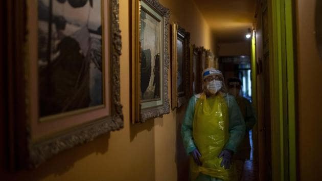 Nurse Isabel Solis, 46, wearing a converted garbage bag apron for protection, walks along a corridor lined with paintings made by Enrique Pastor, 86, during a home visit. Pastor's full-time caregiver tested positive for the virus, leaving his wife to care for the bedridden retired port worker without knowing if either of them has COVID-19. (Emilio Morenatti / AP) Nurse Isabel Solis, 46, wearing a converted garbage bag apron for protection, walks along a corridor lined with paintings made by Enrique Pastor, 86, during a home visit. Pastor's full-time caregiver tested positive for the virus, leaving his wife to care for the bedridden retired port worker without knowing if either of them has COVID-19. (Emilio Morenatti / AP)
