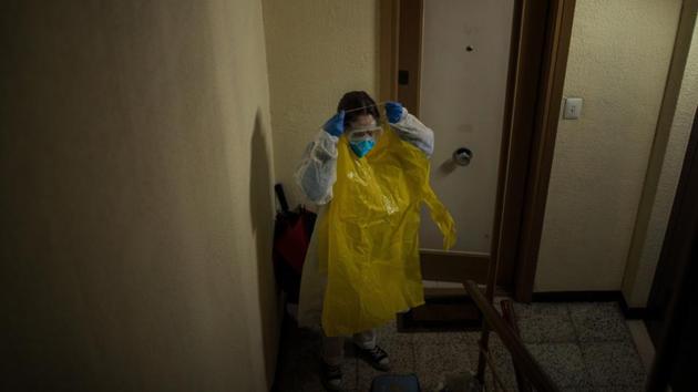 Home care nurse Alba Rodriguez puts on protective gear before visiting a patient in the Poble Sec neighborhood of Barcelona. A pediatric nurse, Rodriguez has gotten creative to try to protect herself, fashioning hazmat suits out of giant yellow garbage bags. "We're like onions," she said of the extra layers. (Emilio Morenatti / AP) Home care nurse Alba Rodriguez puts on protective gear before visiting a patient in the Poble Sec neighborhood of Barcelona. A pediatric nurse, Rodriguez has gotten creative to try to protect herself, fashioning hazmat suits out of giant yellow garbage bags. "We're like onions," she said of the extra layers. (Emilio Morenatti / AP)