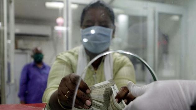 A customer wearing mask counts the money in the Bank as a precuationary measure against coronavirus.(ANI)