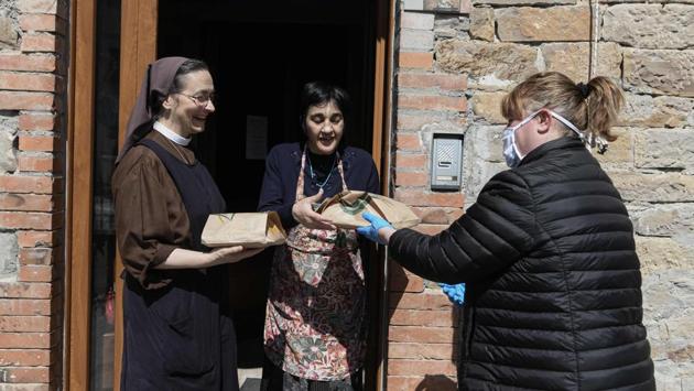 Sara (right), the owner of a local bread shop, delivers fresh bread and Easter cakes at the end of her working day to a nun of a charity house in Vitriola, near Modena. (Piero Cruciatti / AFP) Sara (right), the owner of a local bread shop, delivers fresh bread and Easter cakes at the end of her working day to a nun of a charity house in Vitriola, near Modena. (Piero Cruciatti / AFP)
