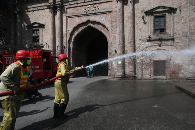 Municipal workers disinfecting a street in Lahore’s old city on March 23, 2020.(Arif Ali/AFP)