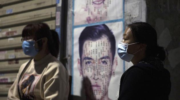 Residents wear masks against the coronavirus near posters, in an old neighbourhood in Wuhan, in central China's Hubei province on Sunday, April 12, 2020. (AP photo) Residents wear masks against the coronavirus near posters, in an old neighbourhood in Wuhan, in central China's Hubei province on Sunday, April 12, 2020. (AP photo)