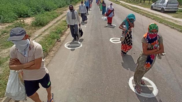 People wait inside marked circles to maintain distance at a food distribution. (HT photo) People wait inside marked circles to maintain distance at a food distribution. (HT photo)