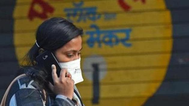 A woman wears a mask as she walks past a closed shutter of a shop that displays lock at Kasba Peth.(Pratham Gokhale/HT Photo)