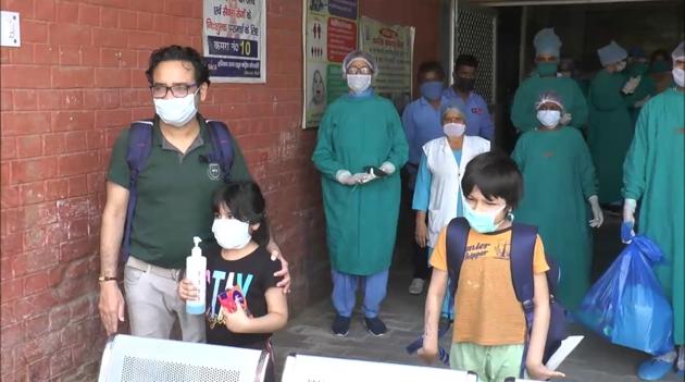 After getting cured of Covid-19, the two kids leaving the hospital with their father.(HT Photo)