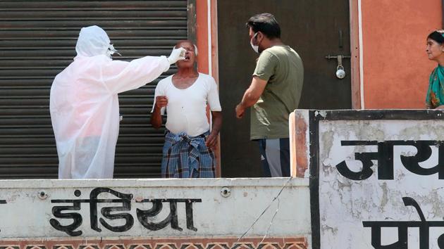 A medical worker in Personal Protective Equipment (PPE) collects a sample from an elderly resident in the walled city area of Jaipur on April 13, 2020. The impact of India’s 21-day national lockdown also banks on disease clusters are being contained effectively, and people are being tested widely and aggressively. (Himanshu Vyas / HT Photo)