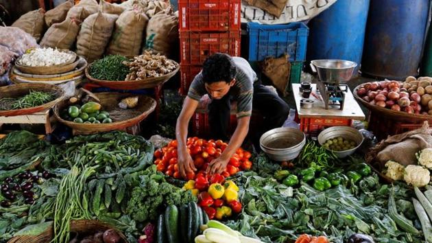Covid-19: A vendor sorts tomatoes as he waits for customers at a vegetable market in Mumbai. Movement of primary articles, such as grains and vegetables, as well as other essential goods have continued to stumble.(REUTERS) Covid-19: A vendor sorts tomatoes as he waits for customers at a vegetable market in Mumbai. Movement of primary articles, such as grains and vegetables, as well as other essential goods have continued to stumble.(REUTERS)