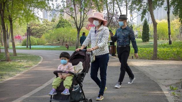 People use face masks to protect against the spread of the new coronavirus as they walk through a public park in Beijing, on Tuesday. (AP Photo) People use face masks to protect against the spread of the new coronavirus as they walk through a public park in Beijing, on Tuesday. (AP Photo)