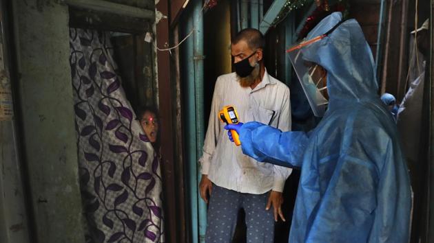 A medical worker checks the temperature of a resident in Dharavi, Mumbai on Monday, April 13, 2020. 1,253 fresh Covid-19 cases were reported in the country on Monday taking the number of cases in the country to 10,444 according to HT’s dashboard. (Rafiq Maqbool / AP)