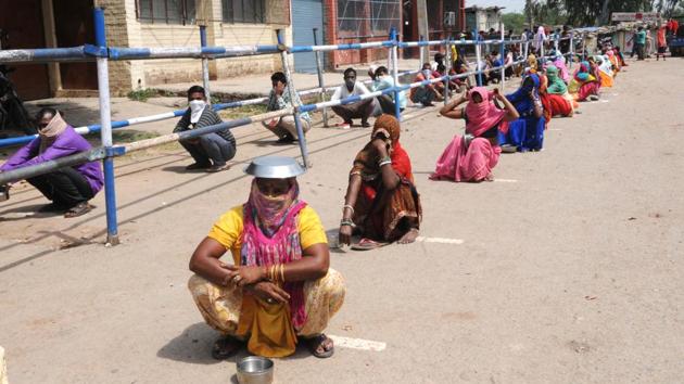 People waiting in a queue for food in the heat of noon in colony no 4 of Industrial Area Phase 1, Chandigarh, amid the curfew on Wednesday.(Keshav Singh/HT photo)