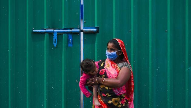 A woman holds her baby as she waits to collect food at Safdarjung Enclave during lockdown, in New Delhi, India, on Tuesday, April 14, 2020.(Amal KS/HT PHOTO)