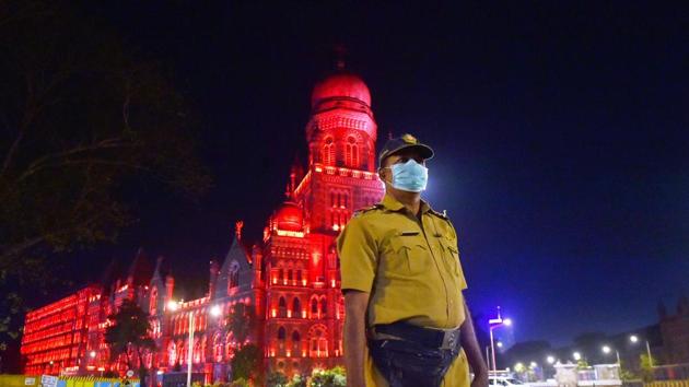 A police official stands in front of the illuminated Brihanmumbai Municipal Corporation (BMC) building in the wake of coronavirus pandemic. (PTI) A police official stands in front of the illuminated Brihanmumbai Municipal Corporation (BMC) building in the wake of coronavirus pandemic. (PTI)