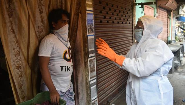 Health department staff in Personal Petective Equipment (PPE) suits collect data from a coronavirus hotspot during lockdown in India.(Photo: Samir Jana/Hindustan Times)