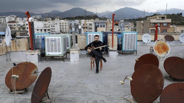Composer and musician Midya Farajnejad, 36, plays the tar on his rooftop surrounded by TV satellite dishes and air conditioning units. Spending days in quarantine, away from the stage of studios, the city’s musicians have their neighbours for an audience, sharing in their emotions though music. (Ebrahim Noroozi / AP) Composer and musician Midya Farajnejad, 36, plays the tar on his rooftop surrounded by TV satellite dishes and air conditioning units. Spending days in quarantine, away from the stage of studios, the city’s musicians have their neighbours for an audience, sharing in their emotions though music. (Ebrahim Noroozi / AP)