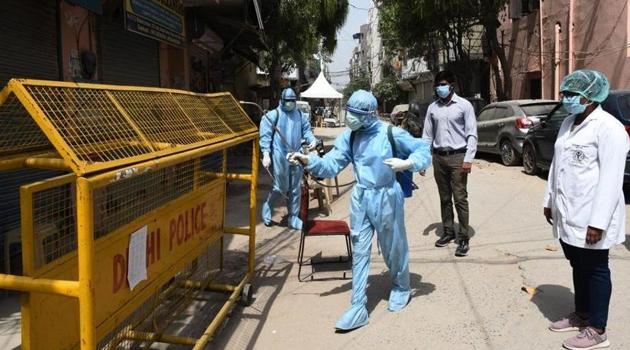 Health workers in Personal Protective Equipment (PPE) kit spray disinfectant to sanitize homes in Delhi’s containment zones.(HT PHOTO.)