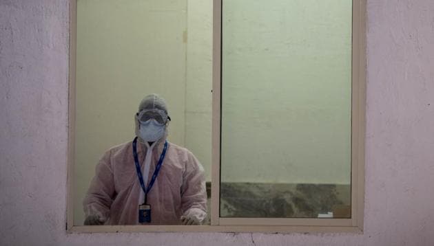 A healthcare worker waits for patients to come for test at a drive through testing site for Covid-19 swab collection.(Photo by Aalok Soni/Hindustan Times)