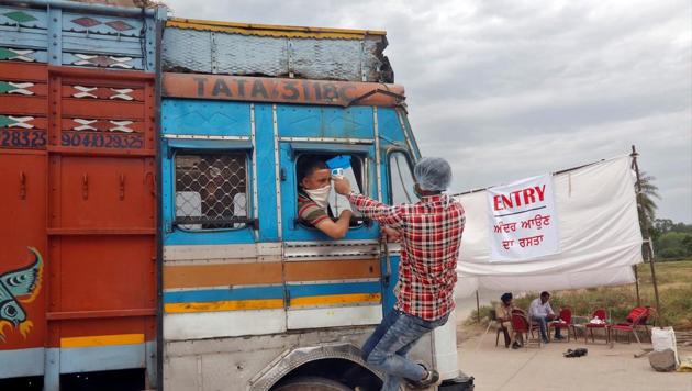 A health worker uses an infrared thermometer to check the temperature of a truck driver at an entry gate of a wholesale grain market during an extended nationwide lockdown to slow the spreading of coronavirus disease in Chandigarh.(Reuters Photo)