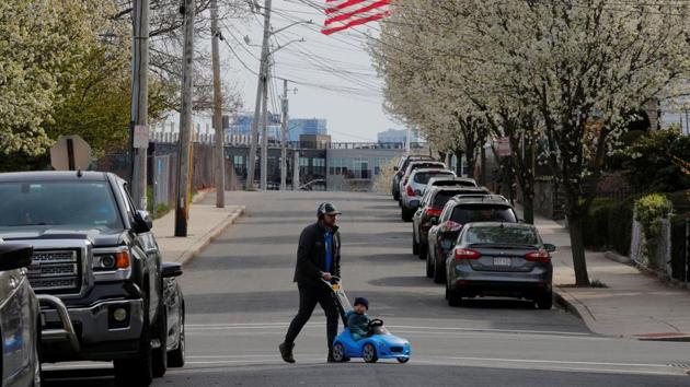 A man and a child cross a street amid the coronavirus disease outbreak in Chelsea, Massachusetts, US. (Reuters Photo)