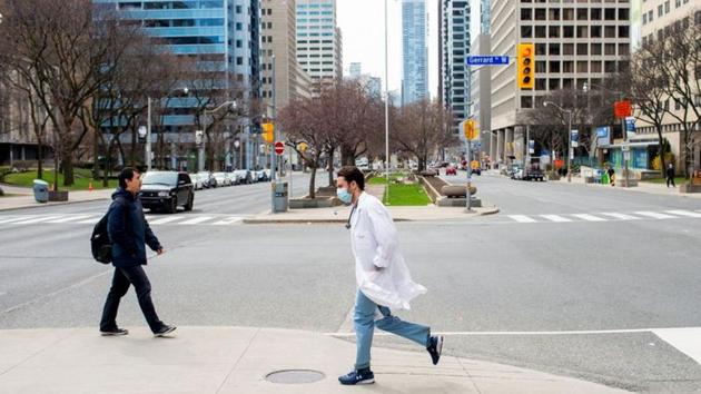 A health care worker runs across University Avenue from Mount Sinai Hospital to Toronto General Hospital as the number of the coronavirus disease (COVID-19) cases continues to grow in Toronto, Ontario.(REUTERS)