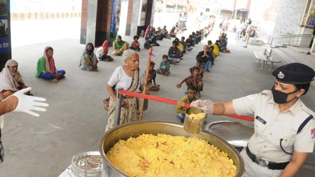 A Railway Protection Force (RPF) personnel distribute food to the needy at Patna Junction during lockdown , April 17,2020(AP Dube/ HT Photo)