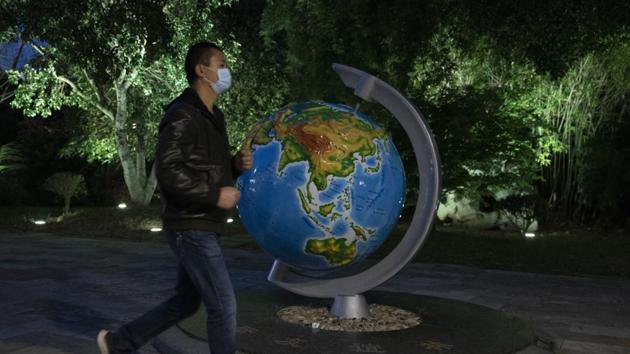 A resident wearing a mask against the coronavirus walks past a giant globe in Wuhan in central China's Hubei province. (AP) A resident wearing a mask against the coronavirus walks past a giant globe in Wuhan in central China's Hubei province. (AP)